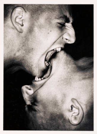 Photo of two men posed with mouths are open, almost interlocking, and biting each other’s chins