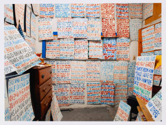 Colorful photo of a small room with walls covered with posters handwritten in blue and red ink