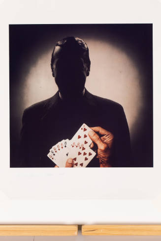 Silhouette of person facing against a hand holding playing cards with a winning hand of gin