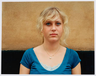 Portrait of a young woman with blond hair, blue eyes, and a blue shirt looking toward viewer