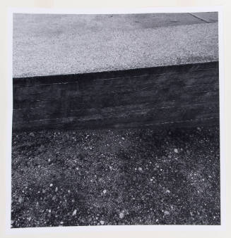 Close-up photograph of graveled surface meeting a short brick wall along center of image